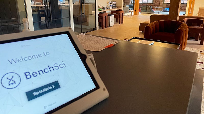 A digital sign-in tablet on a black reception desk displays a 